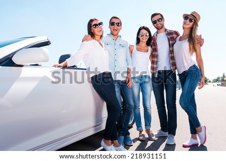 The best friends ever. Low angle view of young happy people bonding to each other and smiling while standing near their convertible