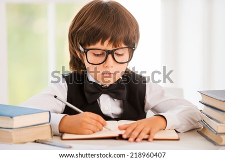 Studying hard. Cute young boy making research while sitting at the desk