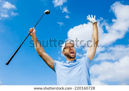 I won! Low angle view of young happy golfer holding driver and raising his arms with blue sky as background