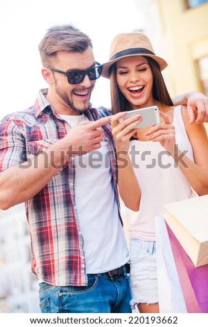 Just look at this picture! Happy young loving couple standing outdoors together and looking at the mobile phone together