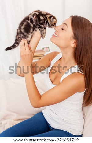 I love you so much! Beautiful young woman holding little kitten in hands and bonding to him