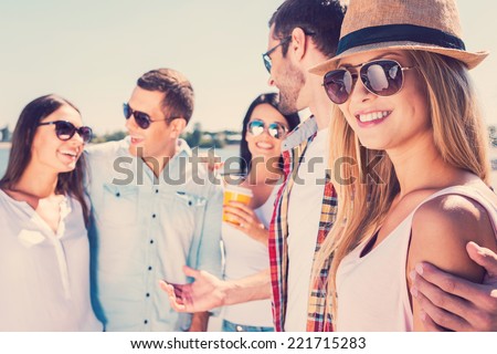Spending great time with friends. Group of young happy people talking to each other while beautiful woman looking at camera and smiling