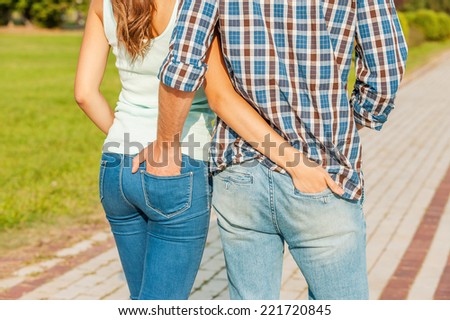 Belong to each other. Young loving couple holding their hands in the pockets of each others jeans while walking.