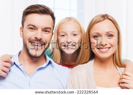 Happy family. Happy family of three bonding to each other and smiling while sitting indoors