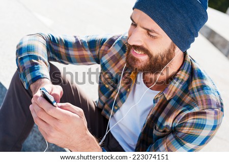 Music is my life Handsome young bearded man smiling while listening to music Music is my life Handsome young bearded man smiling while listening to music