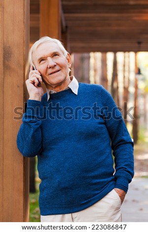 I am so happy to hear from you! Happy senior man talking on the mobile phone and smiling while standing outdoors