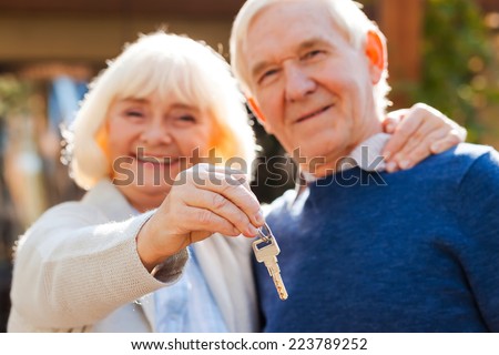 Life is just beginning. Happy senior couple bonding to each other and smiling while woman holding keys in her hand