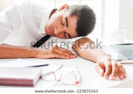 Businessman sleeping. Handsome young Afro-American man in shirt and tie sleeping while sitting at his working place