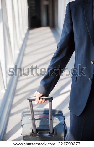 Inside of passenger boarding bridge. Close-up of businessman carrying suitcase while walking through a passenger boarding bridge