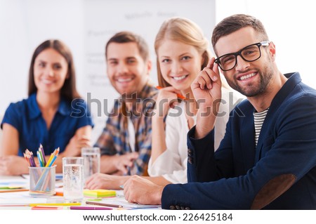 Creative team. Group of confident business people in smart casual wear sitting at the table together and smiling
