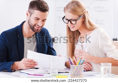Discussing contract together. Two confident business people in smart casual wear sitting together at the table and discussing something while looking at the document