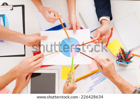 Group discussion. Top view of business people pointing diagram together while sitting at the table