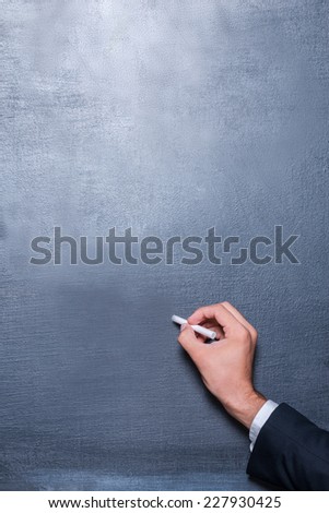 Drawing on the blackboard. Close-up of man writing on the blackboard by chalk