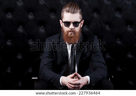 In his own style. Portrait of a confident young bearded man in shirt and tie sitting in chair