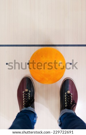 Ready for a game. Close-up of a bowling ball lying near human legs