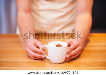 Fresh coffee for you. Close-up of male barista serving cup of fresh coffee for you