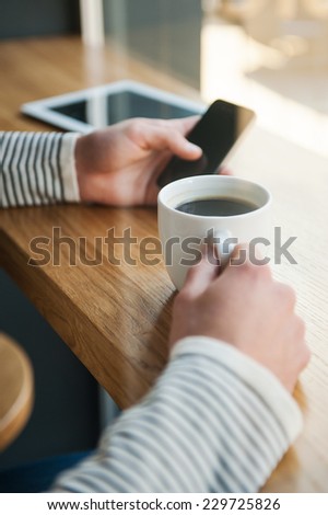 No minute without technologies. Close-up of man holding digital tablet while enjoying coffee in cafe