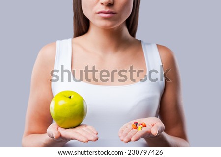 Make your choice!  Cropped picture of young woman holding an apple and pills in her hands