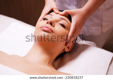 Removing stress. Beautiful young woman lying on back while massage therapist massaging her head