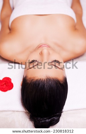 SPA serenity. Top view of beautiful young woman wrapped in towel lying on massage table and keeping eyes close