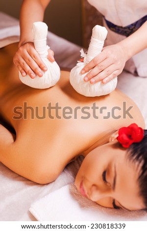 Massage for tired muscles. Top view of beautiful young woman lying on front while massage therapist massaging her back