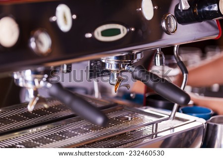 Coffee maker. Close-up image of metal espresso machine with someone working in the background