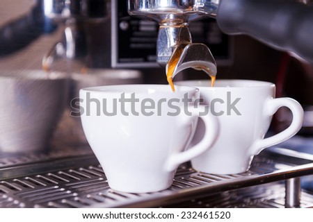 Fresh made coffee. Close-up image of two cups filling with fresh coffee