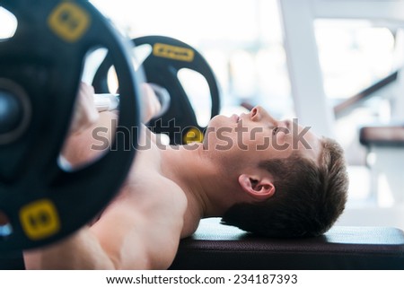 Bench press. Confident young muscular man working out on bench press