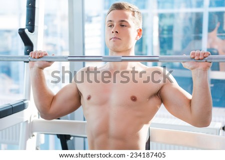 Working out on bench press. Concentrated young muscular man working out on bench press