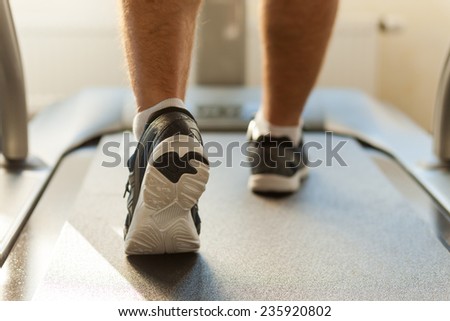 Walking on treadmill. Close-up of man walking by treadmill in sports club