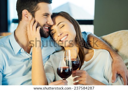 Love is a great feeling. Beautiful young loving couple sitting close to each other and drinking red wine