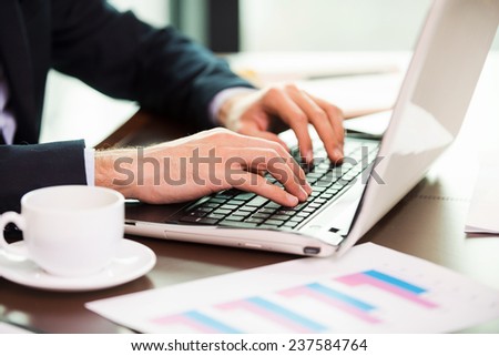 Confident business expert. Close-up of man in formalwear working on laptop while sitting at his working place