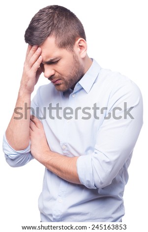 Feeling exhausted. Side view of young man in shirt touching his head and keeping eyes closed while standing against white background