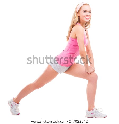 Beauty exercising. Full length of beautiful pin-up blond hair woman in pink shirt doing stretching exercises while standing isolated on white background