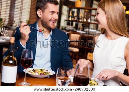 Enjoying meal together. Beautiful young loving couple enjoying dinner at the restaurant