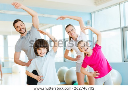 Family exercising. Happy sporty family doing stretching exercises in sports club