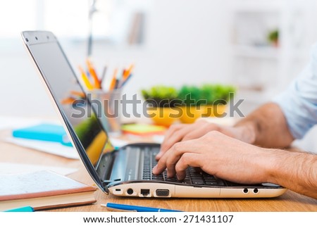 Working hard to meet deadlines. Close-up of young man working on laptop while sitting at his working place