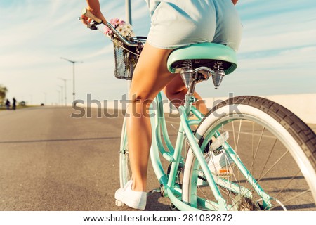 Woman riding bicycle. Close-up rear view image of young women riding on her bicycle along the road