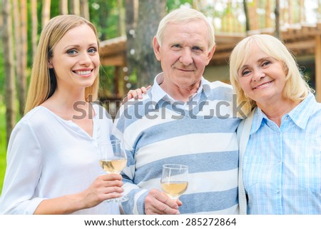 Young woman with parents. Happy young woman bonding to her senior parents while standing outdoors together