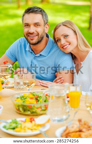 Dinner at the fresh air. Top view of happy young loving couple enjoying meal together while sitting at the dining table outdoors