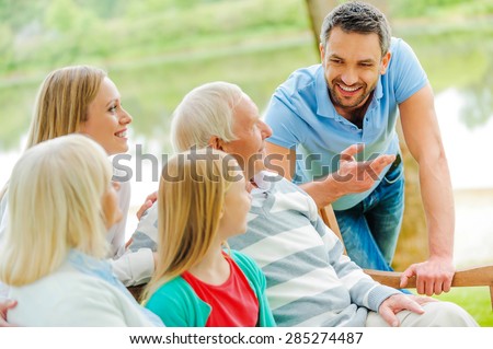 Spending time with family. Happy family of five people talking to each other and smiling while sitting outdoors together