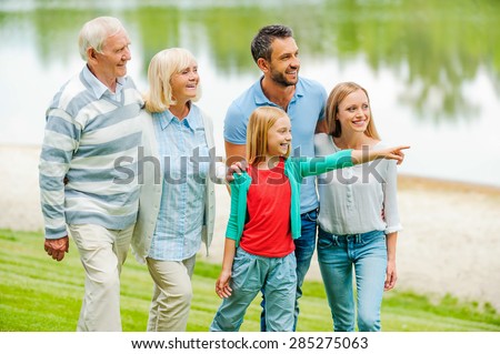 Spending quality time with family. Happy young family walking outdoors together while little girl pointing away and smiling