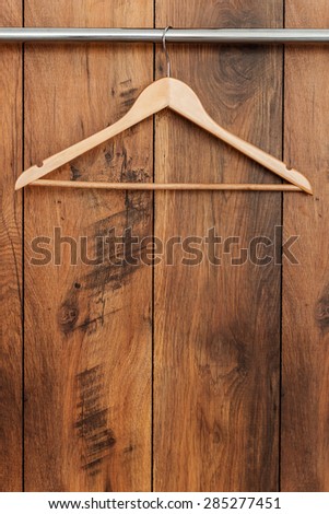Wooden coat hanger. Close-up of hanger hanging against wooden grain