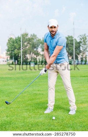 Last swing into the aim. Confident young manplaying golf while standing on the golf course