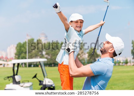 Joy of great game. Excited young man picking up his son while standing on the golf course