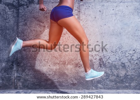 Running towards a healthy life.  Close-up of young woman with beautiful legs running against a concrete wall