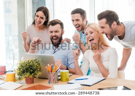 Everyday winners. Group of happy business people in smart casual wear looking at the laptop and gesturing