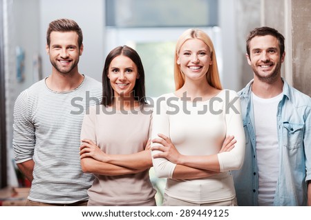 Young and successful team. Four young business people in smart casual wear standing close to each other and smiling discussing