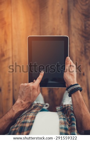 Technologies make life easier. Top view of man using digital tablet while standing on the wooden floor