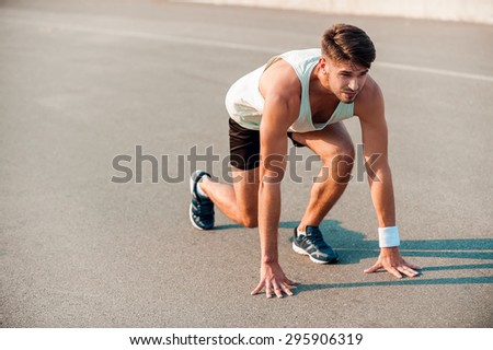 Total concentration. Confident young muscular man standing in starting line and looking forward